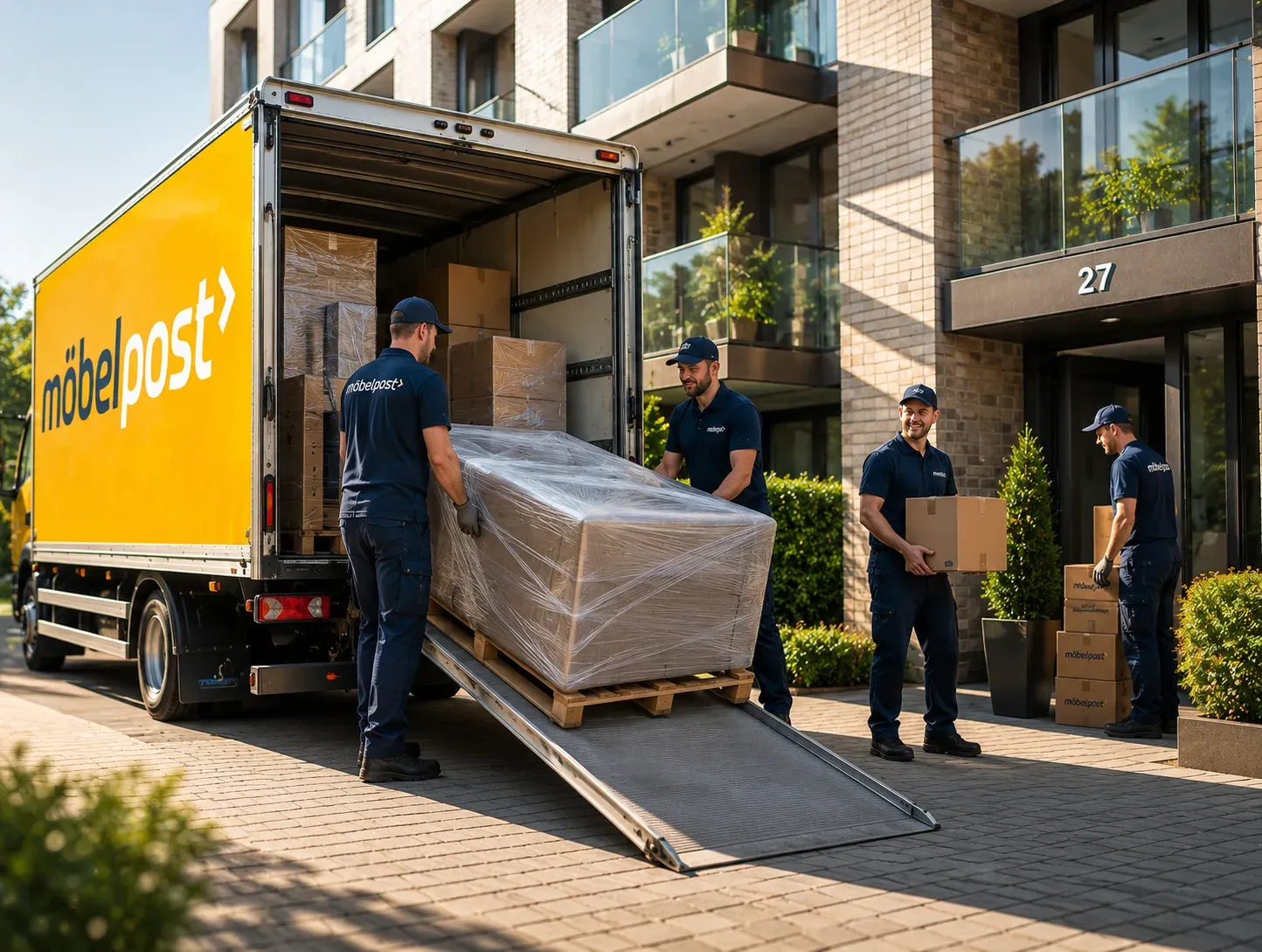 Möbelpost-Mitarbeiter laden ein verpacktes Möbelstück in einen LKW
